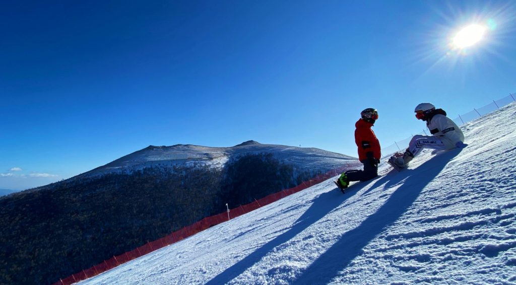Deux hommes en veste rouge et pantalon noir font du ski de randonnée sur une montagne enneigée pendant