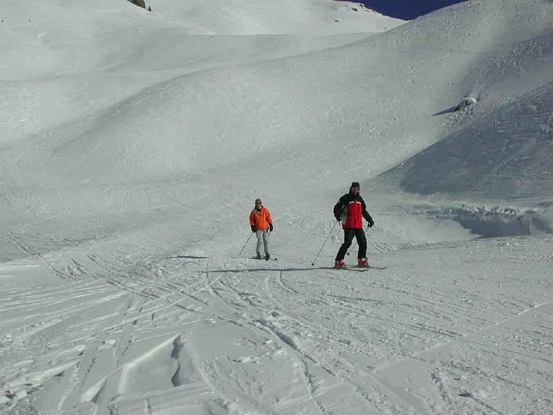 Deux skieurs dévalent une pente recouverte de neige.